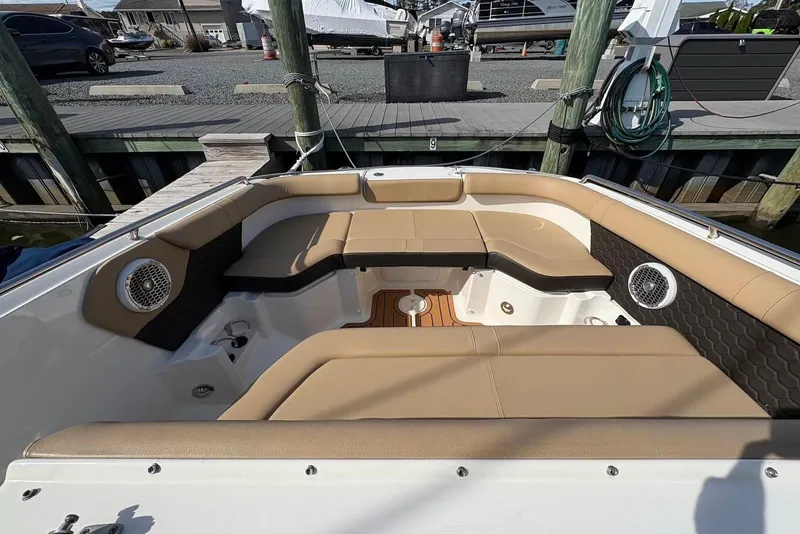 Slide: The Image of 2018 Sea Ray SDX 250 Outboard boat interior with tan seating and speakers at dock. - 9