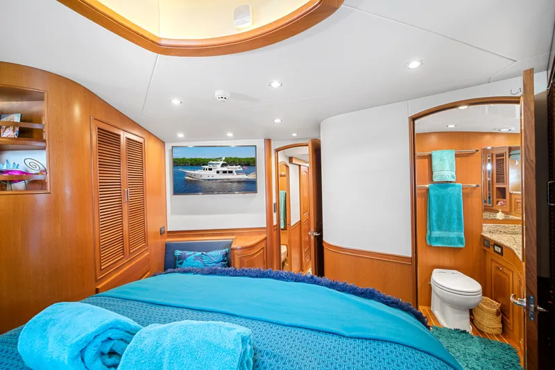 Slide: The Image of Luxurious 2017 Fleming 65 yacht bedroom with ensuite bathroom, featuring elegant wood finishes and vibrant decor. - 13