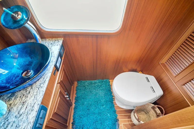 Slide: The Image of Luxurious 2017 Fleming 65 yacht bathroom with blue glass sink and wooden interior. - 23