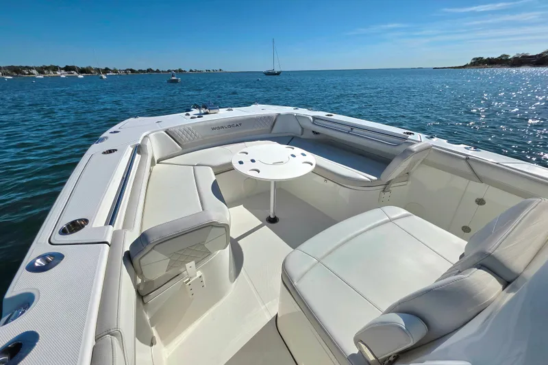 Slide: The Image of 2024 World Cat 325 CC boat interior with seating and table on calm water. - 12