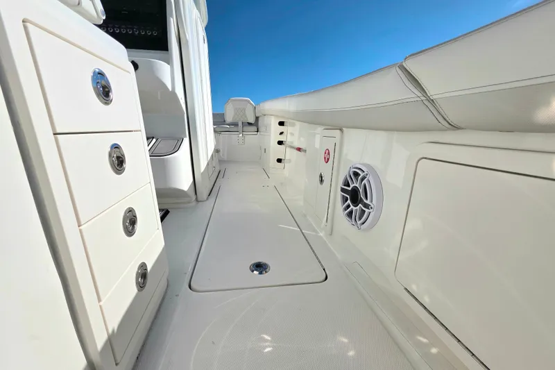 Slide: The Image of 2024 World Cat 325 CC boat interior with storage and speaker, under clear blue sky. - 13