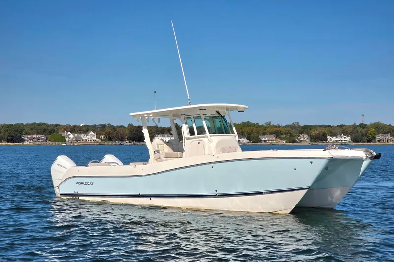 Slide: The Image of 2024 World Cat 325 CC boat on calm water, clear sky background. - 2