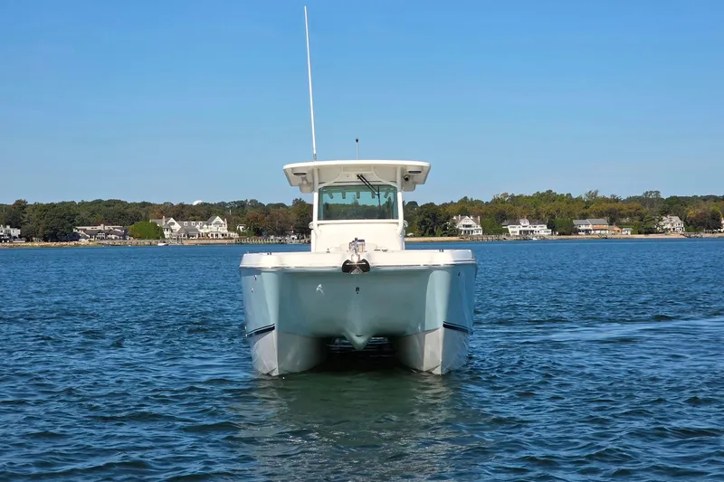 Slide: The Image of 2024 World Cat 325 CC boat on calm water with coastal homes in the background. - 22