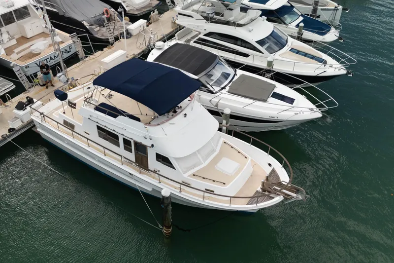 Slide: The Image of 1982 CHB Classic Trawler 41 docked among modern yachts in a marina. - 6