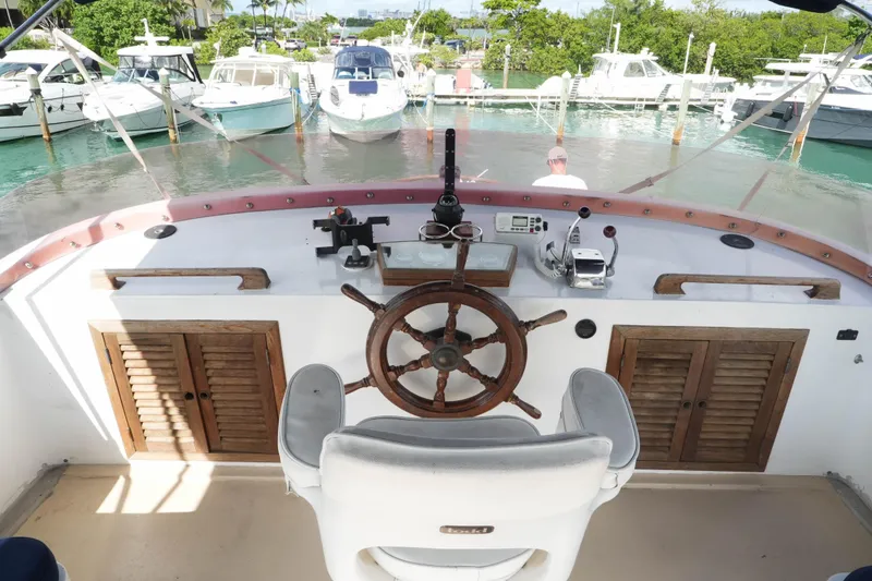 Slide: The Image of 1982 CHB Classic Trawler 41 helm with wooden wheel, docked among boats. - 8