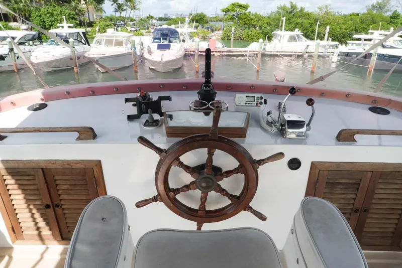 Slide: The Image of 1982 CHB Classic Trawler 41 helm with wooden wheel, docked in a marina. - 9