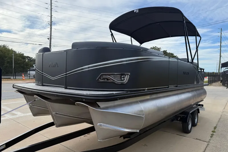 Slide: The Image of 2026 Avalon LSZ Rear Fish pontoon boat with sleek black design on a trailer. - 2