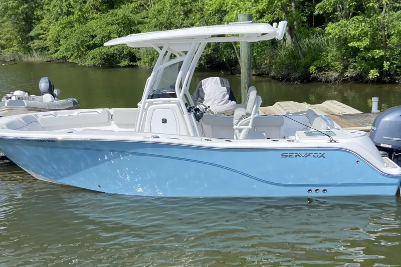 The Image of 2022 Sea Fox 228 Commander boat docked on a calm lake with lush greenery. - 0