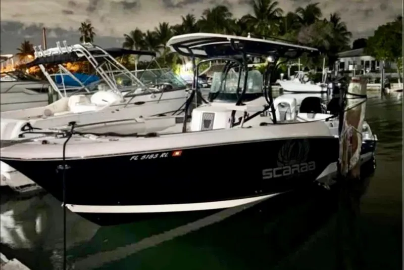 Slide: The Image of 2017 Wellcraft 262 Scarab Offshore boat docked at night, surrounded by palm trees. - 1