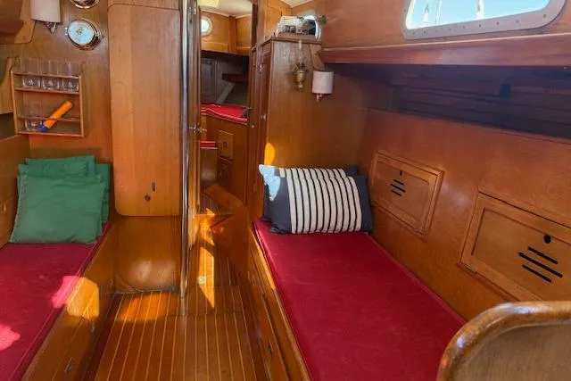 Slide: The Image of Interior of a 1970 Hinckley Pilot 35 sailboat with wooden finish and red cushions. - 10