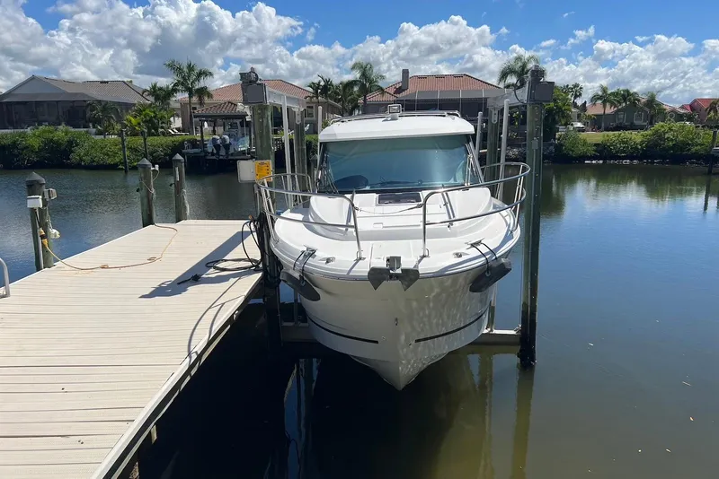 Slide: The Image of 2024 Jeanneau NC Weekender 895 docked by waterfront homes under a sunny sky. - 1