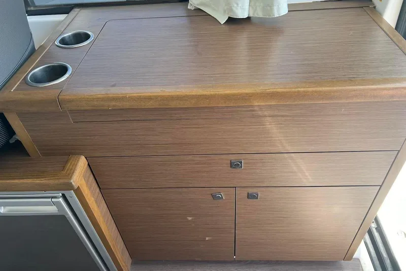 Slide: The Image of 2024 Jeanneau NC Weekender 895 interior with wooden cabinetry and cup holders. - 12