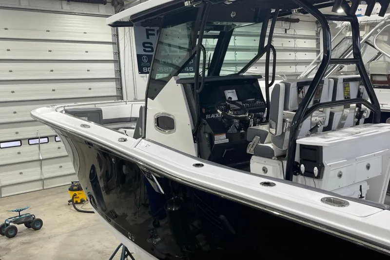 Slide: The Image of 2019 Blackfin 272 CC boat in a garage, showcasing interior and helm. - 16