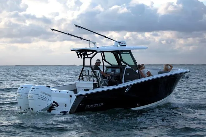 Slide: The Image of 2019 Blackfin 272 CC boat for sale in showroom, featuring sleek black hull. - 2