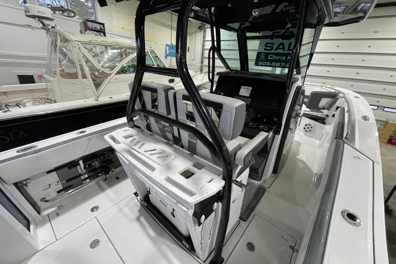 Slide: The Image of 2019 Blackfin 272 CC boat interior with seating and control console in a showroom. - 40