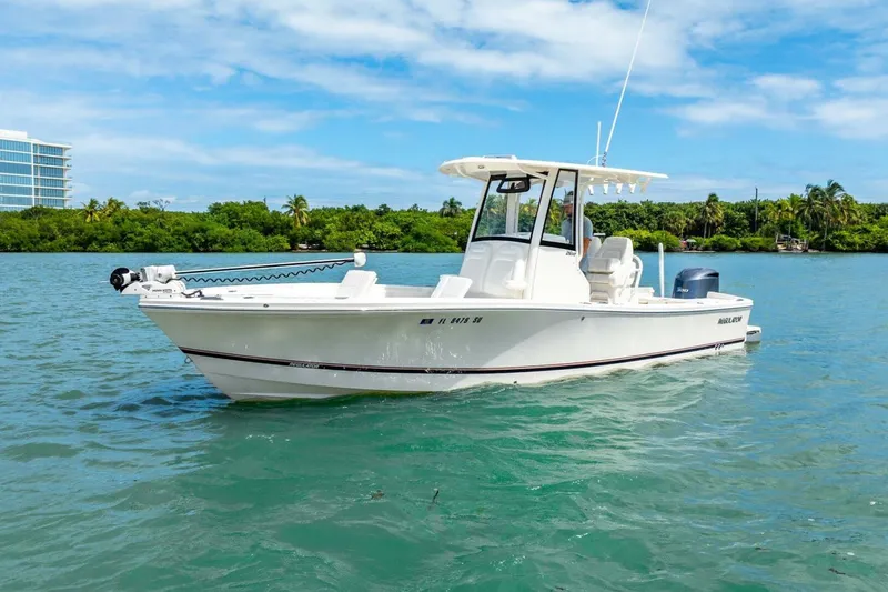 Slide: The Image of 2021 Regulator 26XO boat on clear blue water with lush green shoreline. - 10