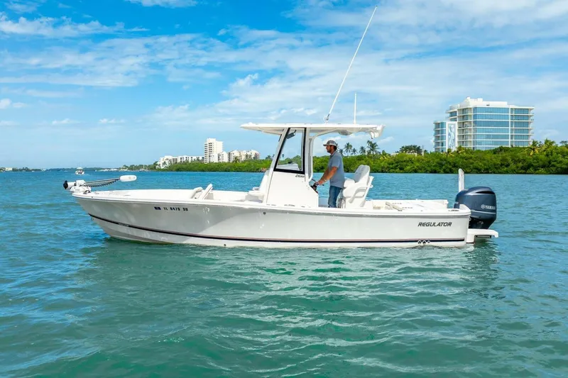 Slide: The Image of 2021 Regulator 26XO boat cruising on a sunny day near modern buildings. - 11