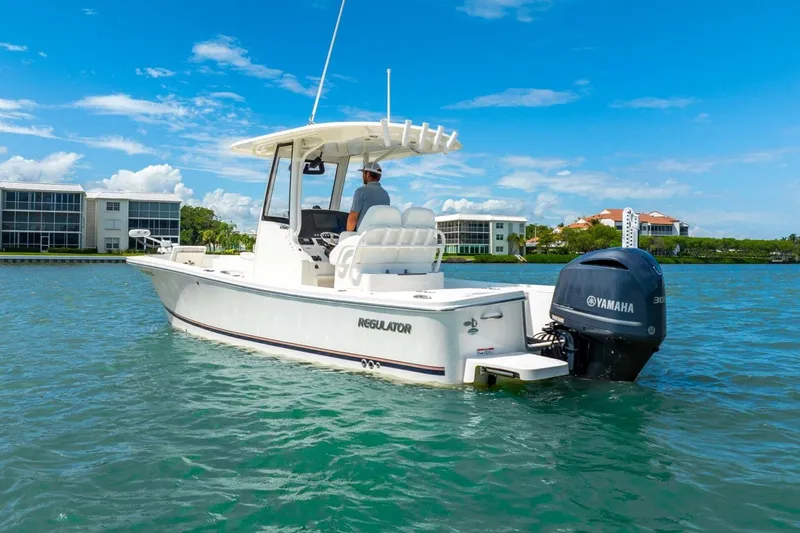 Slide: The Image of 2021 Regulator 26XO boat on water with Yamaha engine, clear sky, and waterfront buildings. - 12