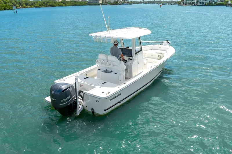 Slide: The Image of 2021 Regulator 26XO boat cruising on clear blue water with Yamaha engine. - 15