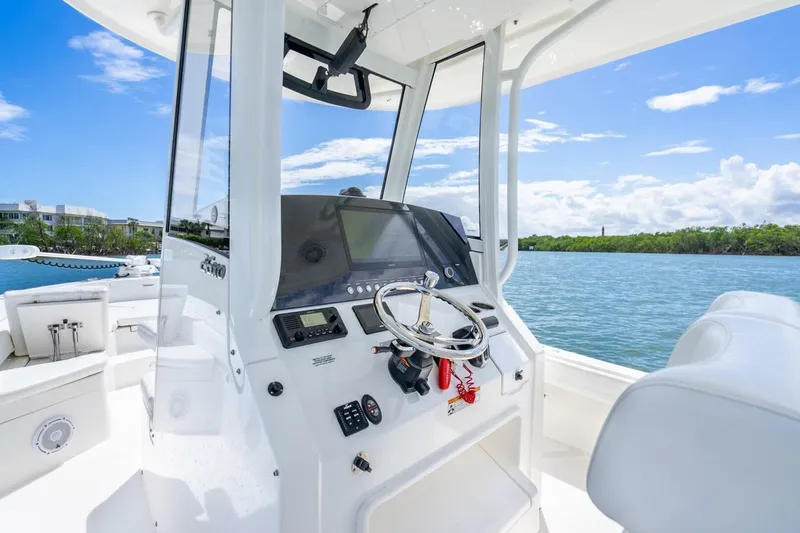 Slide: The Image of 2021 Regulator 26XO boat interior with steering wheel, dashboard, and water view. - 26