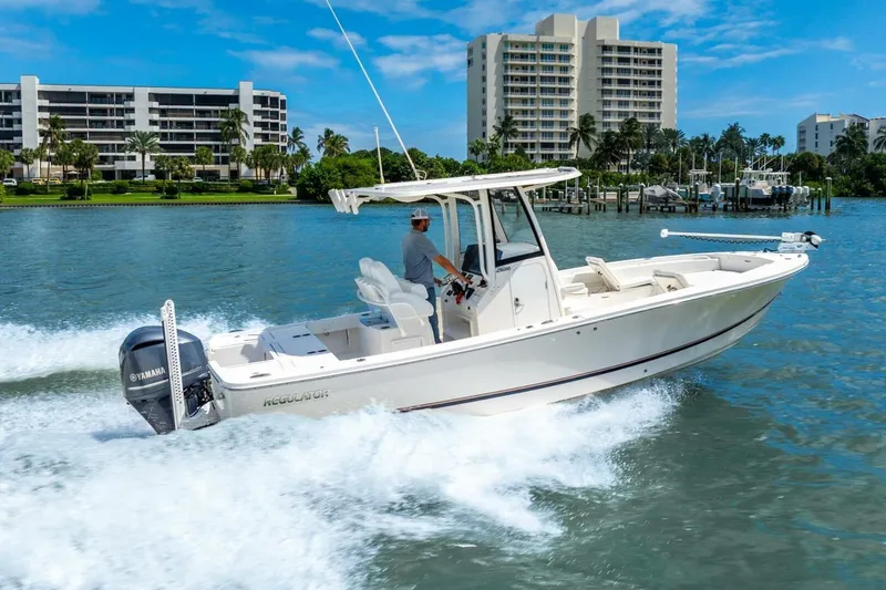 Slide: The Image of 2021 Regulator 26XO boat cruising on water near modern waterfront buildings. - 4