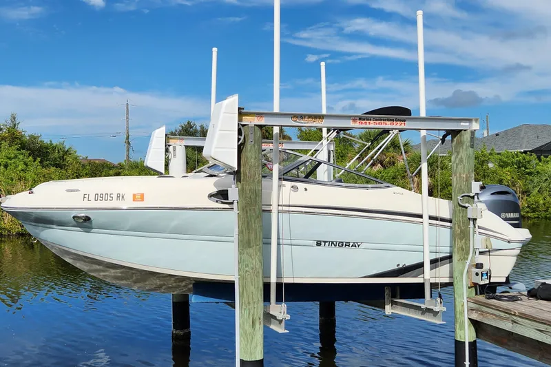 The Image of 2017 Stingray 214 LR boat on lift, docked by water, clear sky background. - 0