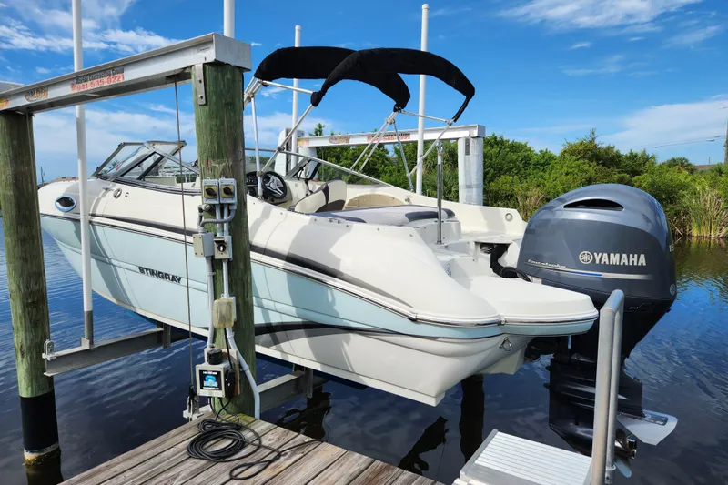 Slide: The Image of 2017 Stingray 214 LR boat with Yamaha engine on a lift by the water. - 1
