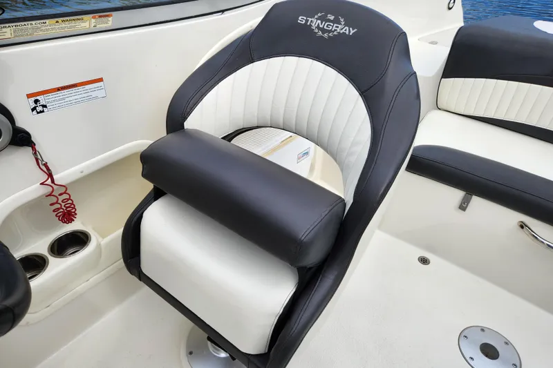 Slide: The Image of 2017 Stingray 214 LR boat seat with black and white upholstery, cup holders, and safety cord. - 11