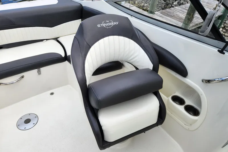 Slide: The Image of 2017 Stingray 214 LR boat interior with black and white seating and cup holders. - 12