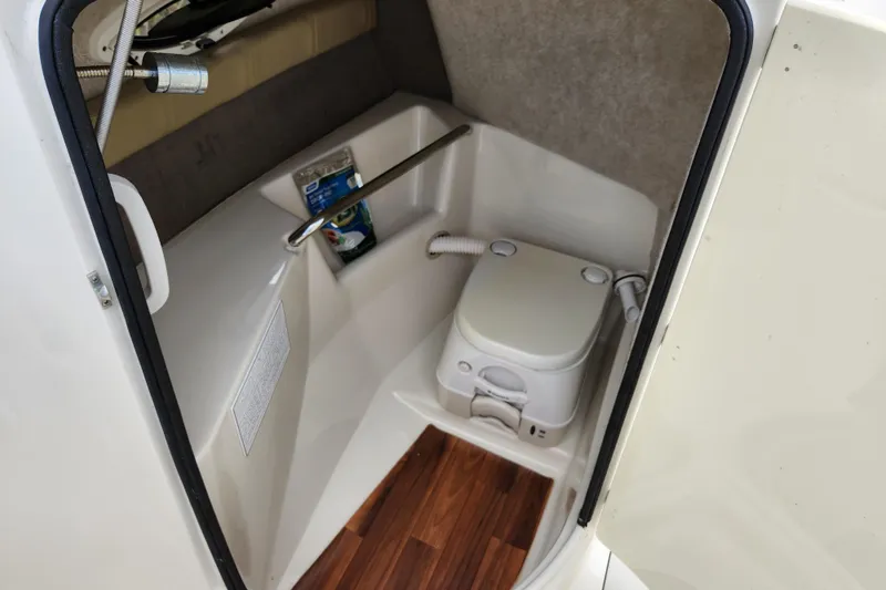 Slide: The Image of 2017 Stingray 214 LR boat interior with compact marine toilet and wooden flooring. - 18