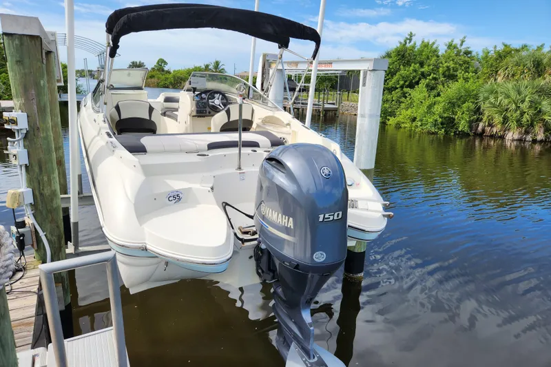 Slide: The Image of 2017 Stingray 214 LR boat with Yamaha 150 engine docked on calm water. - 2