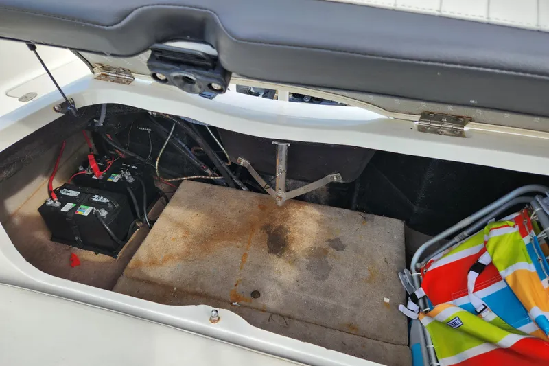 Slide: The Image of Open storage compartment in 2017 Stingray 214 LR boat with battery and colorful beach chair. - 23