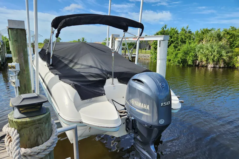 Slide: The Image of 2017 Stingray 214 LR boat with Yamaha 150 engine docked by a lush riverside. - 27