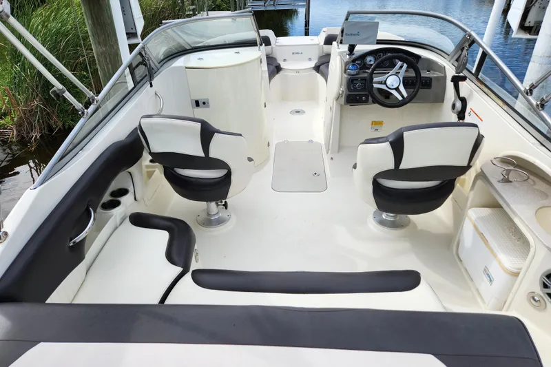 Slide: The Image of 2017 Stingray 214 LR boat interior with dual seats and steering wheel, docked by water. - 3