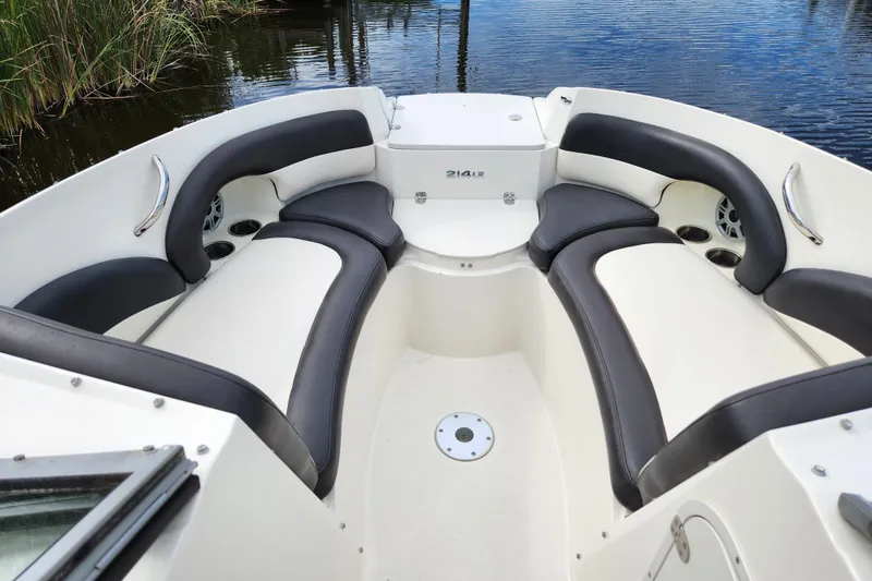 Slide: The Image of 2017 Stingray 214 LR boat interior with cushioned seating and sleek design on calm water. - 5