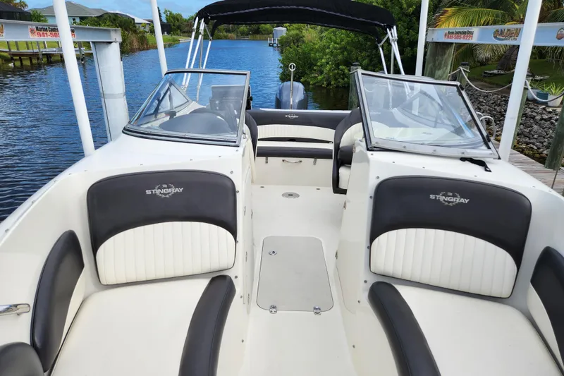 Slide: The Image of 2017 Stingray 214 LR boat interior with seating, windshield, and waterway backdrop. - 7