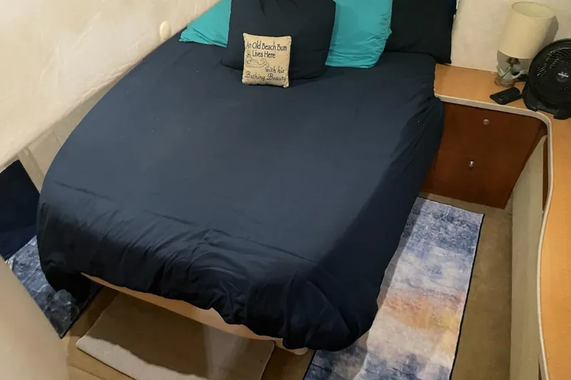 Slide: The Image of Cozy bedroom interior of 1997 Silverton 402 Motor Yacht with navy bedding and decorative pillows. - 8