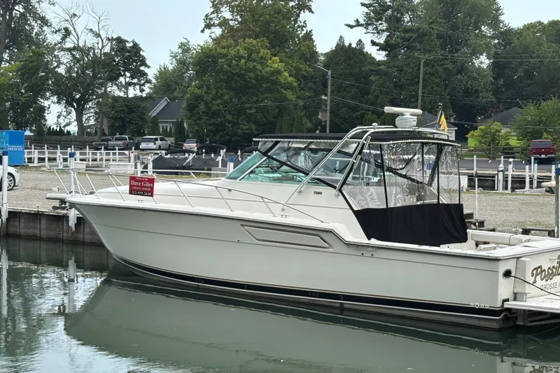 The Image of 1992 Tiara Yachts 4300 Open docked at a marina, surrounded by trees and parked cars. - 0