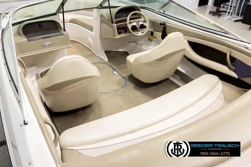 Slide: The Image of 1999 Four Winns 180 Horizon boat interior with beige seating and dashboard, Reeder-Trausch Marine logo. - 10