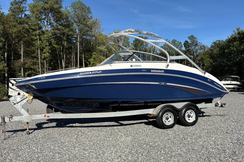 The Image of 2014 Yamaha Boats 242 Limited S on trailer, parked outdoors with trees in background. - 1