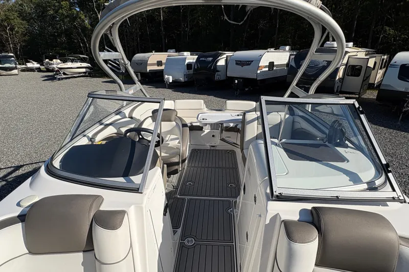 Slide: The Image of 2014 Yamaha Boats 242 Limited S interior with seating and dashboard, parked near RVs. - 15