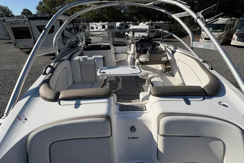 Slide: The Image of 2014 Yamaha Boats 242 Limited S interior with seating and table, parked among RVs. - 7