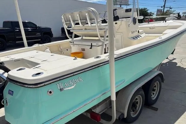 Slide: The Image of 2014 BlackJack 224 Bay boat on trailer, light blue hull, parked outdoors. - 4