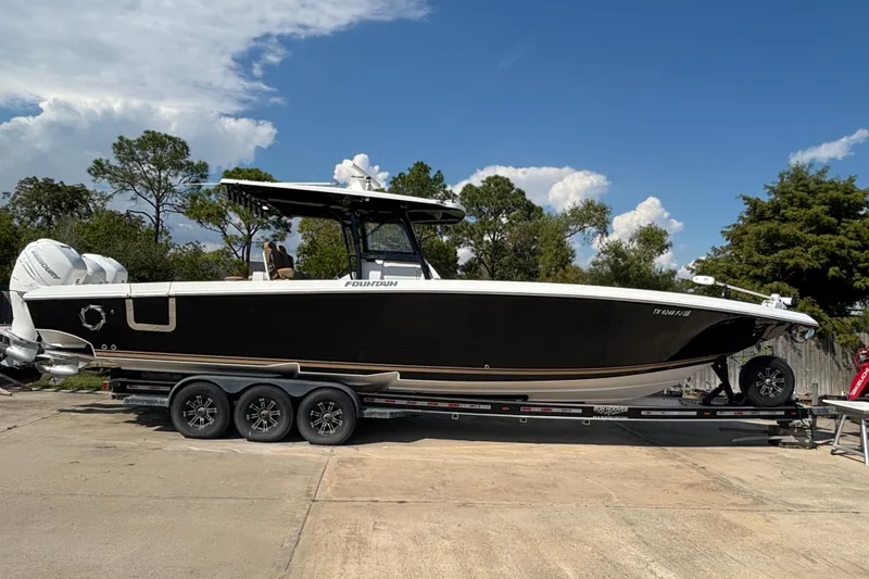 The Image of 2019 Fountain 38 CC LS boat on trailer, parked outdoors under blue sky. - 0