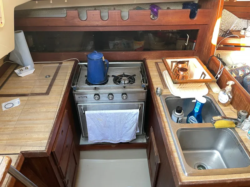 Slide: The Image of 1982 O'Day 34 sailboat galley with stove, sink, and wooden cabinetry. - 6