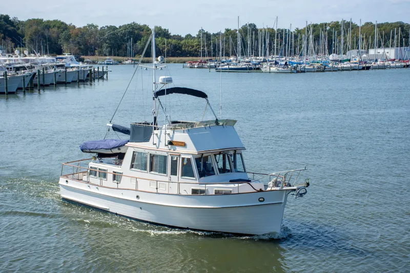 Slide: The Image of 1990 Grand Banks 36 Classic yacht cruising in a marina with sailboats in the background. - 2