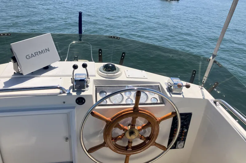 Slide: The Image of 1990 Grand Banks 36 Classic yacht deck with wooden railings and scenic marina view. - 22