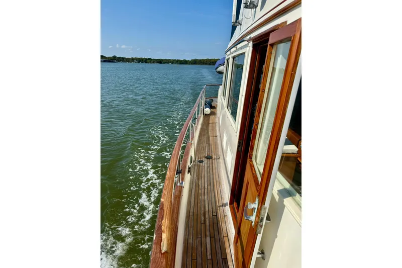 Slide: The Image of 1990 Grand Banks 36 Classic yacht on calm water, showcasing its elegant design. - 23