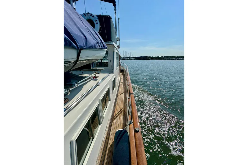 Slide: The Image of 1990 Grand Banks 36 Classic yacht cruising on a calm lake with forested shoreline. - 24