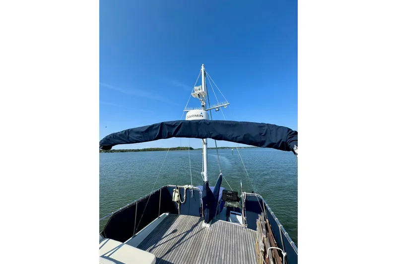 Slide: The Image of 1990 Grand Banks 36 Classic yacht deck with seating and steering wheel, overlooking calm waters. - 35